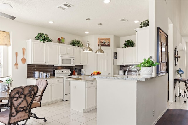 kitchen with decorative light fixtures, backsplash, white appliances, a kitchen island with sink, and white cabinets