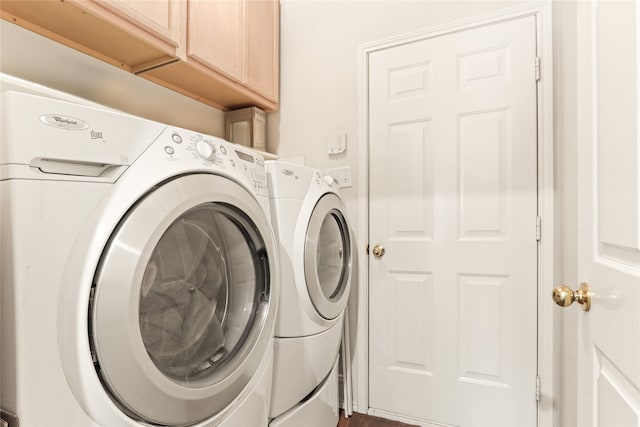 clothes washing area featuring cabinets and separate washer and dryer