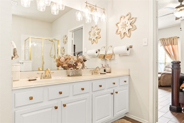 bathroom featuring ceiling fan, a textured ceiling, a shower with door, and vanity