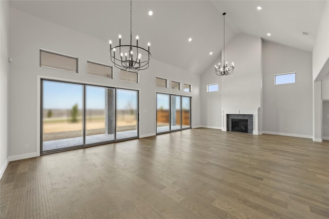 unfurnished living room with wood finished floors, a fireplace, baseboards, and an inviting chandelier