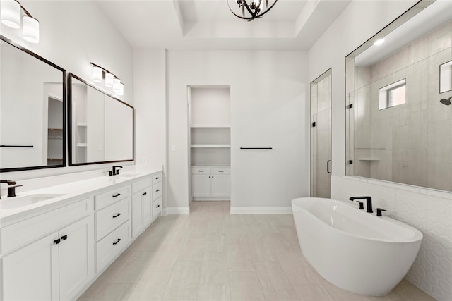 full bathroom with double vanity, a shower stall, a tray ceiling, and a sink