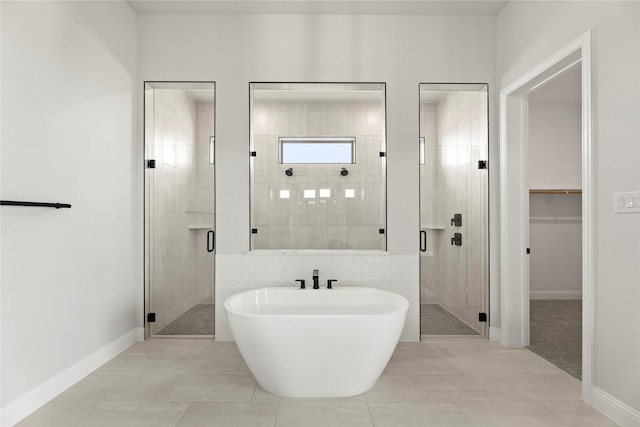 bathroom with a stall shower, baseboards, a soaking tub, tile patterned flooring, and a spacious closet