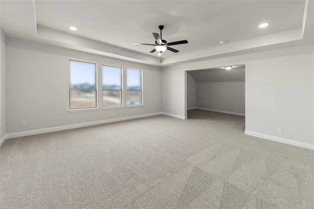 unfurnished bedroom featuring recessed lighting, baseboards, a raised ceiling, and light colored carpet