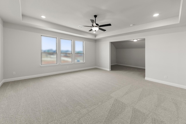 unfurnished bedroom featuring a tray ceiling, light colored carpet, baseboards, and recessed lighting