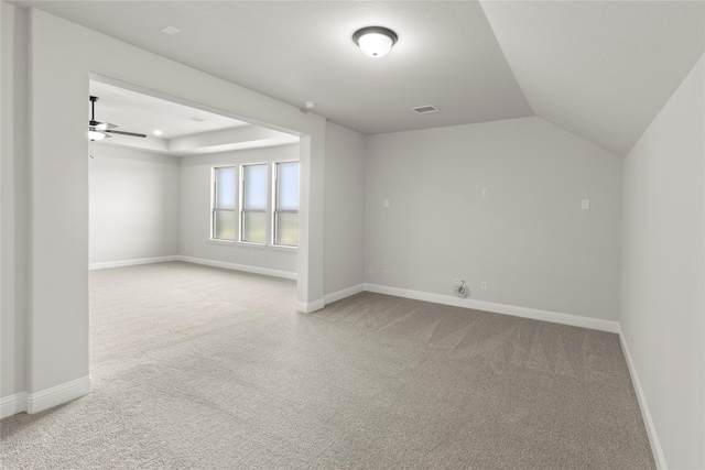 unfurnished room with a tray ceiling, light carpet, visible vents, and baseboards