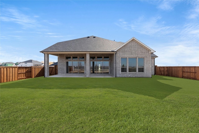 back of house with brick siding, a patio, a shingled roof, a lawn, and a fenced backyard