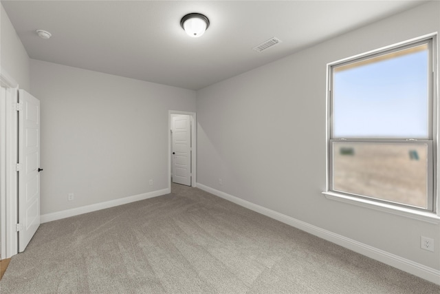 carpeted empty room with visible vents and baseboards