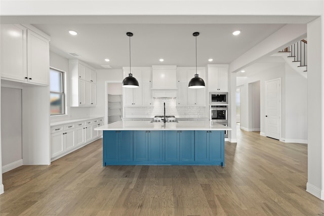 kitchen with light wood-style flooring, appliances with stainless steel finishes, white cabinets, and light countertops