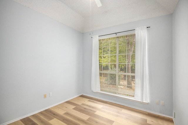 empty room with ceiling fan, light hardwood / wood-style floors, and a textured ceiling