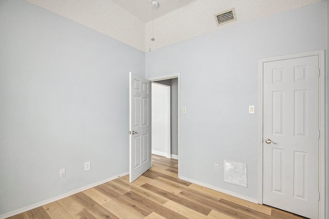 spare room with a textured ceiling and light wood-type flooring