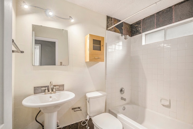 full bathroom featuring sink, tiled shower / bath combo, a textured ceiling, and toilet