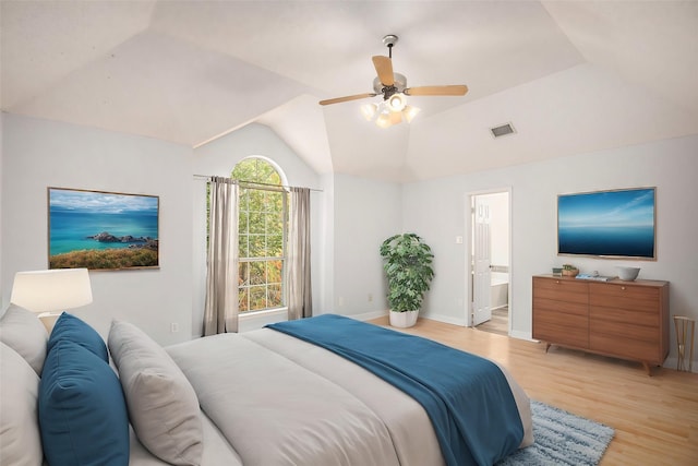 bedroom featuring ceiling fan, ensuite bath, lofted ceiling, and light wood-type flooring