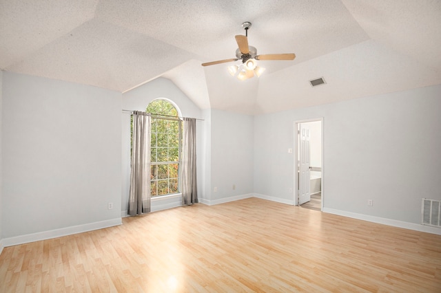 unfurnished room featuring lofted ceiling, a textured ceiling, and light wood-type flooring