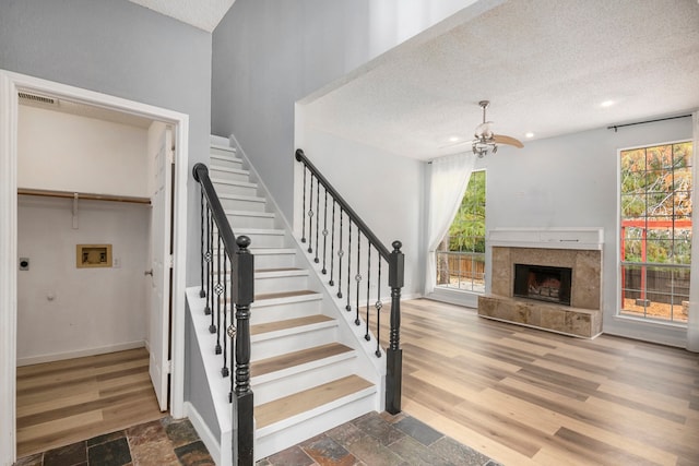 staircase with ceiling fan, hardwood / wood-style floors, and a textured ceiling