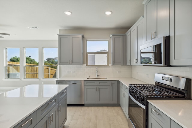 kitchen featuring gray cabinets, sink, appliances with stainless steel finishes, and light hardwood / wood-style flooring