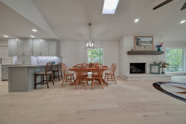 dining space with light hardwood / wood-style flooring, lofted ceiling, a fireplace, and a wealth of natural light