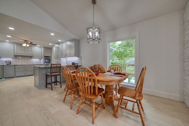 dining space with light hardwood / wood-style floors, lofted ceiling, and ceiling fan with notable chandelier