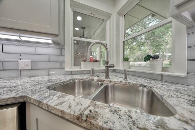 details featuring white cabinetry, sink, and light stone counters