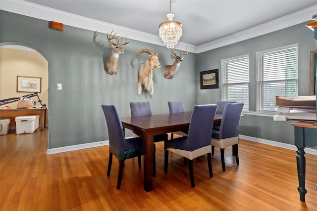 dining space featuring light hardwood / wood-style floors, crown molding, and an inviting chandelier