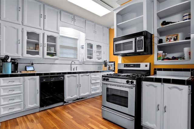 kitchen with tasteful backsplash, appliances with stainless steel finishes, light wood-type flooring, tile counters, and white cabinets