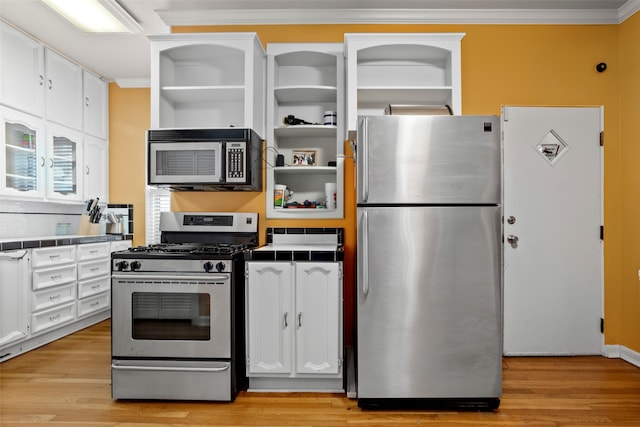 kitchen featuring tile countertops, appliances with stainless steel finishes, white cabinetry, and light hardwood / wood-style floors