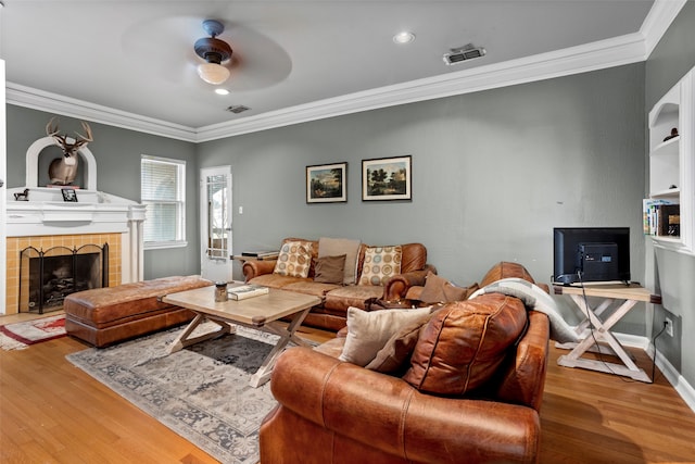 living room with crown molding, hardwood / wood-style flooring, a fireplace, and ceiling fan