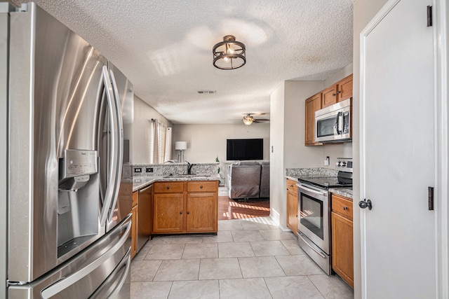 kitchen with sink, appliances with stainless steel finishes, a textured ceiling, and ceiling fan