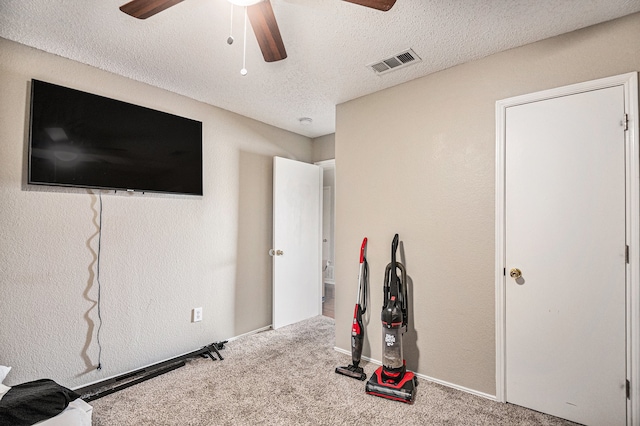 workout room with ceiling fan, carpet flooring, and a textured ceiling