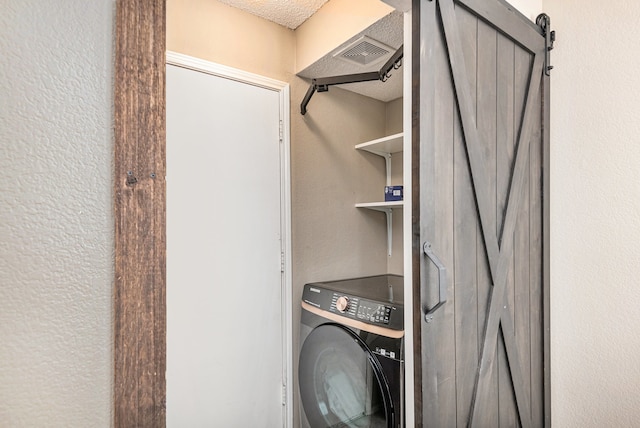 washroom with washer / dryer, a barn door, and a textured ceiling