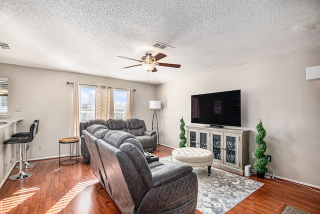 living room featuring a textured ceiling, dark hardwood / wood-style floors, and ceiling fan