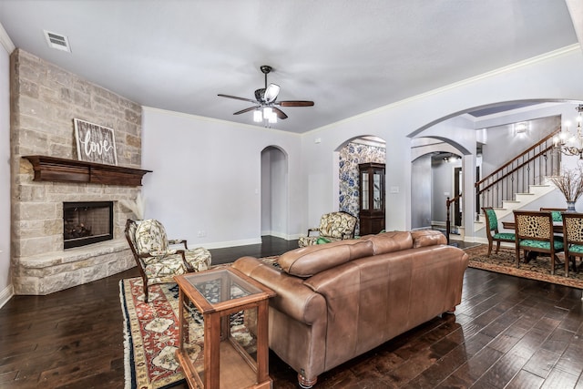 living room with a stone fireplace, ornamental molding, ceiling fan, and dark hardwood / wood-style flooring