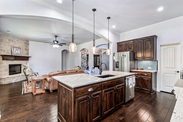 kitchen with an island with sink, stainless steel appliances, dark brown cabinetry, decorative light fixtures, and dark hardwood / wood-style floors