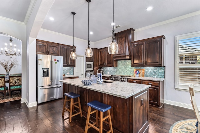 kitchen featuring hanging light fixtures, stainless steel appliances, dark wood-type flooring, and an island with sink