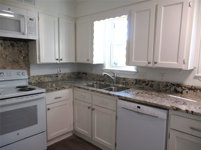 kitchen featuring white cabinets, light stone countertops, dark hardwood / wood-style floors, sink, and white appliances