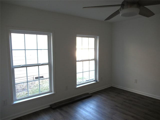 empty room featuring a healthy amount of sunlight, ceiling fan, and dark hardwood / wood-style flooring