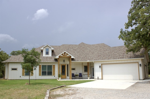 view of front of home with driveway, a garage, roof with shingles, board and batten siding, and a front yard