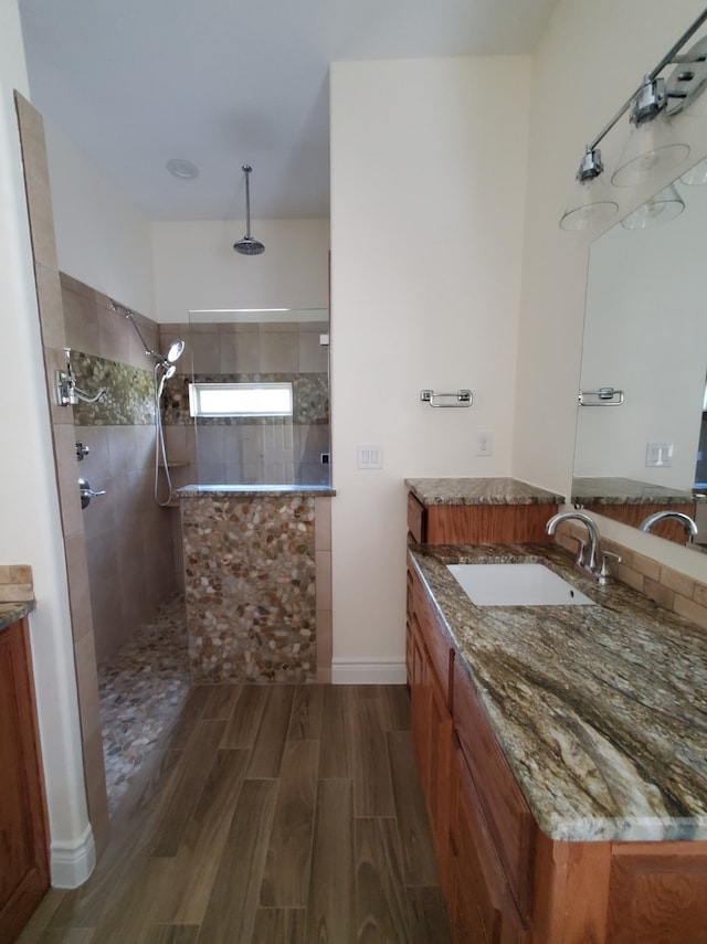 bathroom with wood tiled floor, vanity, baseboards, and walk in shower