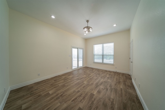 empty room with a notable chandelier and dark hardwood / wood-style flooring