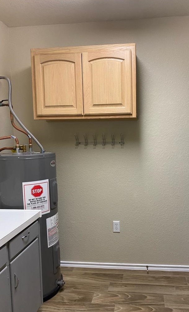 washroom featuring water heater, baseboards, and dark wood-style flooring