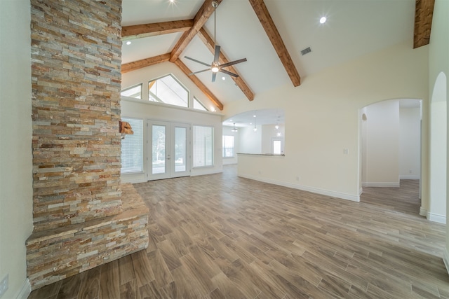 unfurnished living room featuring hardwood / wood-style floors, beam ceiling, ceiling fan, high vaulted ceiling, and french doors