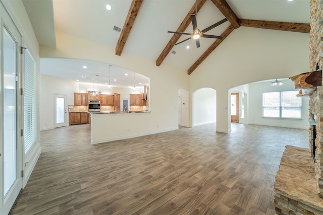 unfurnished living room with dark wood-type flooring, high vaulted ceiling, beamed ceiling, and ceiling fan with notable chandelier