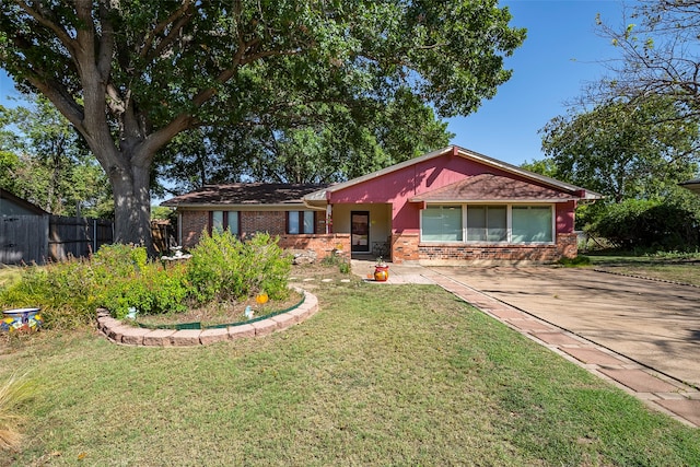 single story home featuring a front yard, fence, and brick siding