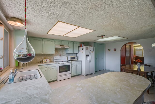 kitchen with tasteful backsplash, sink, white appliances, green cabinetry, and a textured ceiling