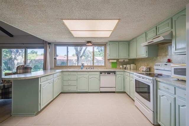 kitchen with sink, a textured ceiling, kitchen peninsula, green cabinets, and white appliances