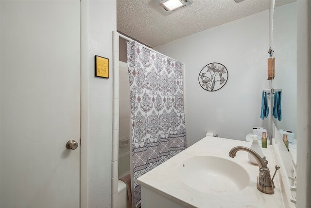 bathroom with vanity, a textured ceiling, and shower / bathtub combination with curtain