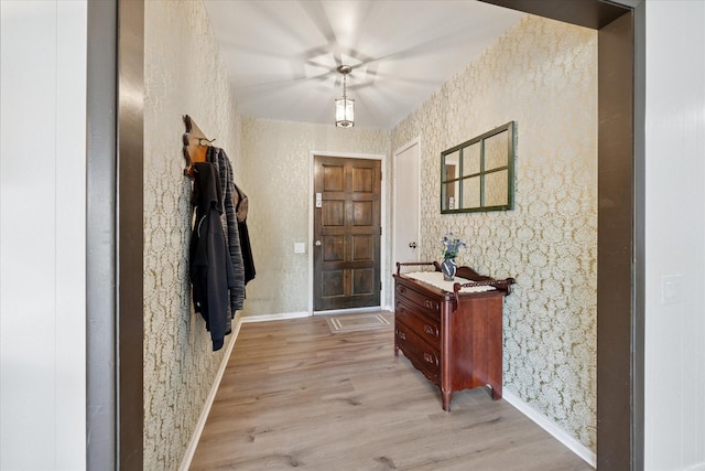 foyer entrance featuring wallpapered walls, light wood-type flooring, and baseboards