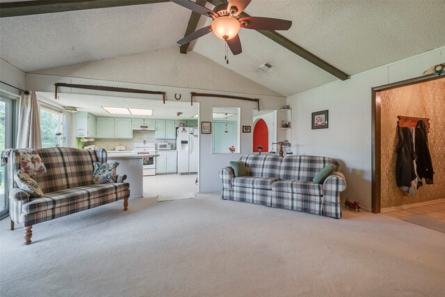 carpeted living room with ceiling fan, a textured ceiling, and vaulted ceiling with beams