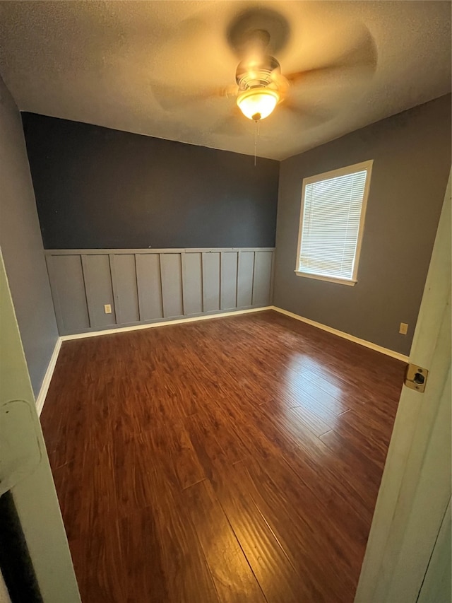 empty room featuring a textured ceiling, ceiling fan, and dark hardwood / wood-style flooring