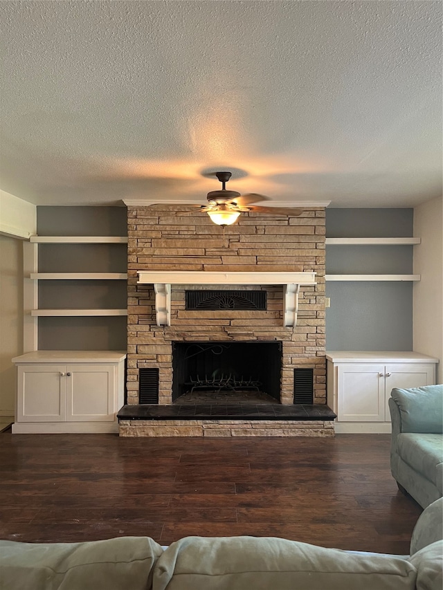 unfurnished living room featuring a stone fireplace, a textured ceiling, ceiling fan, and dark hardwood / wood-style floors