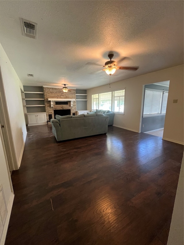 unfurnished living room with a fireplace, dark hardwood / wood-style flooring, a textured ceiling, built in shelves, and ceiling fan